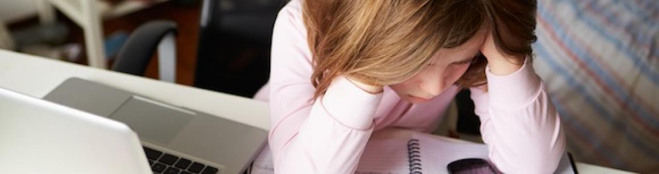 bimba-con-le-mani-nei-capelli-di-fronte-a-smartphone-e-computer.jpg